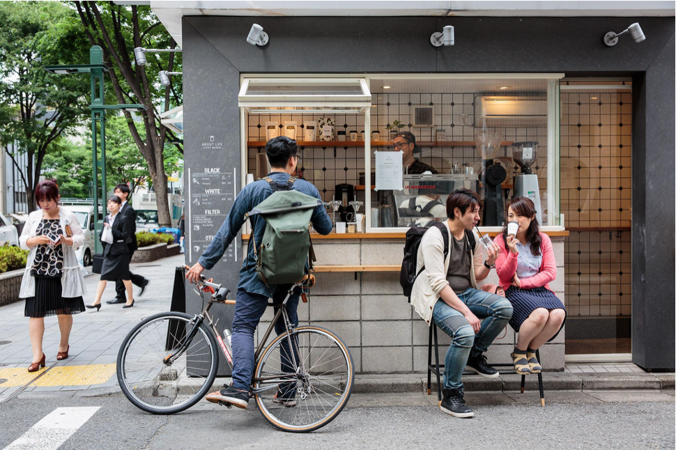 Customers enjoying drinks at a modern Asian street-side coffee kiosk