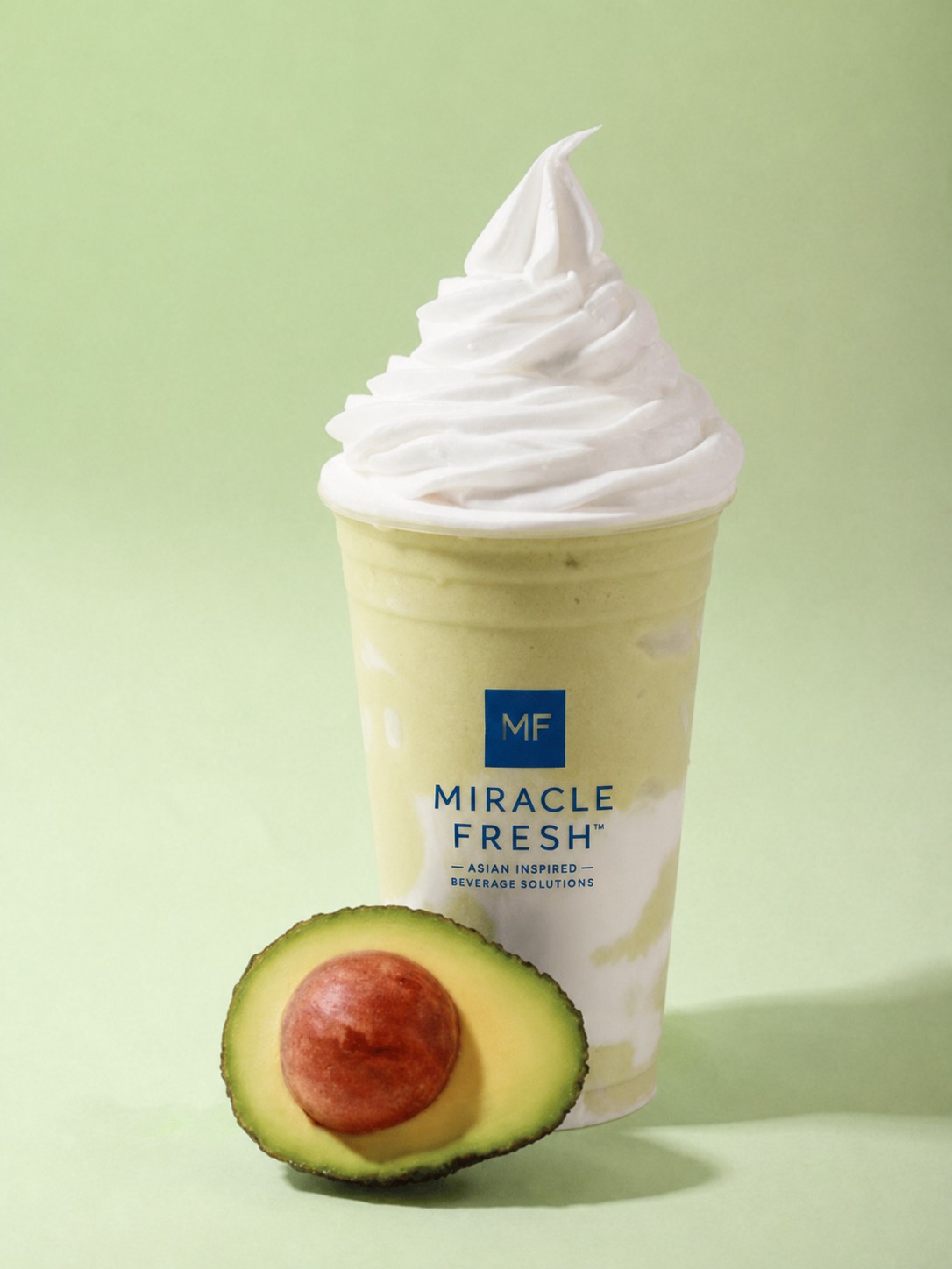 Avocado coconut swirl slush with soft-serve topping and a halved avocado
