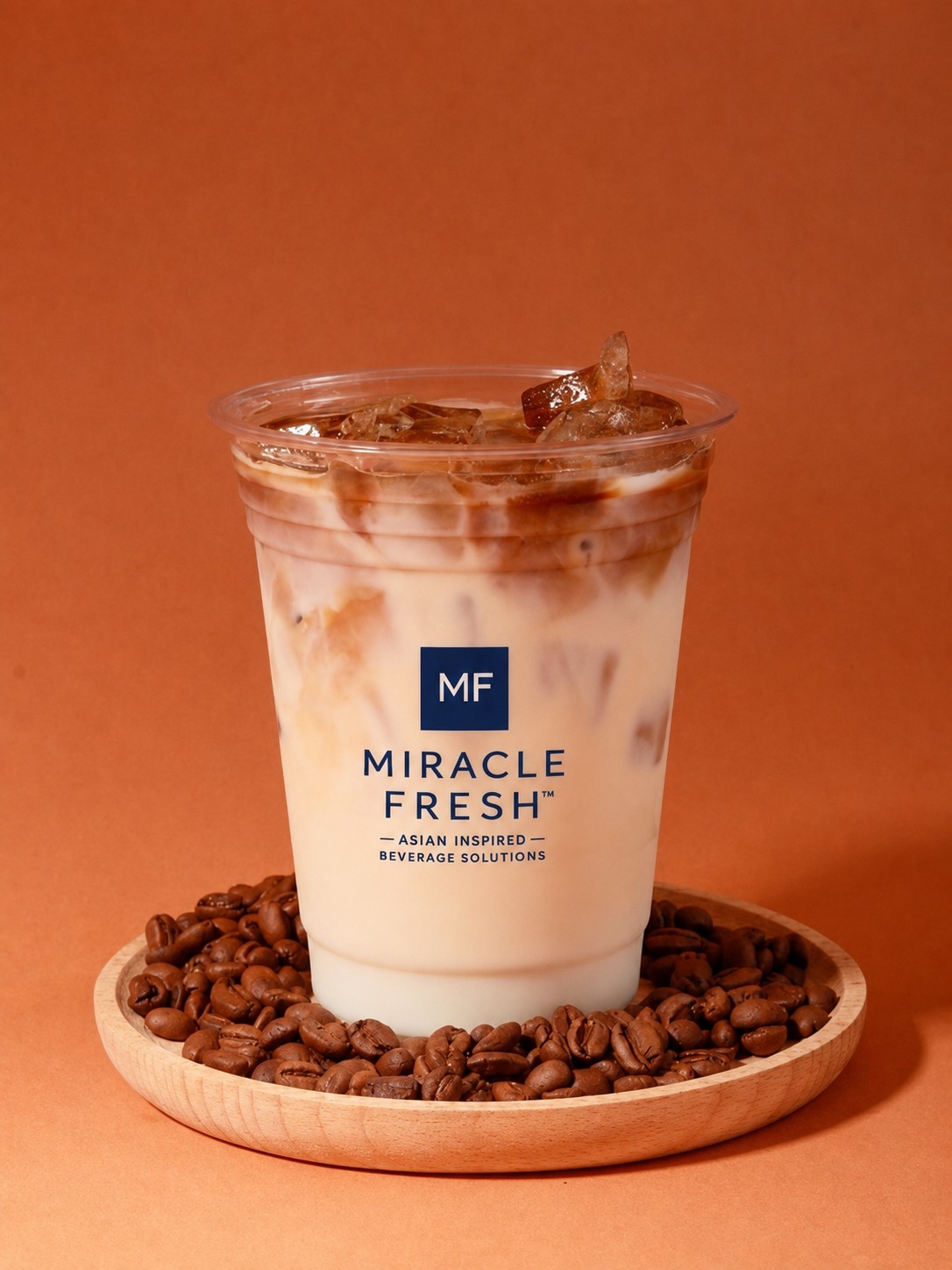Iced oat latte with condensed milk and coffee beans beside a Miracle Fresh cup