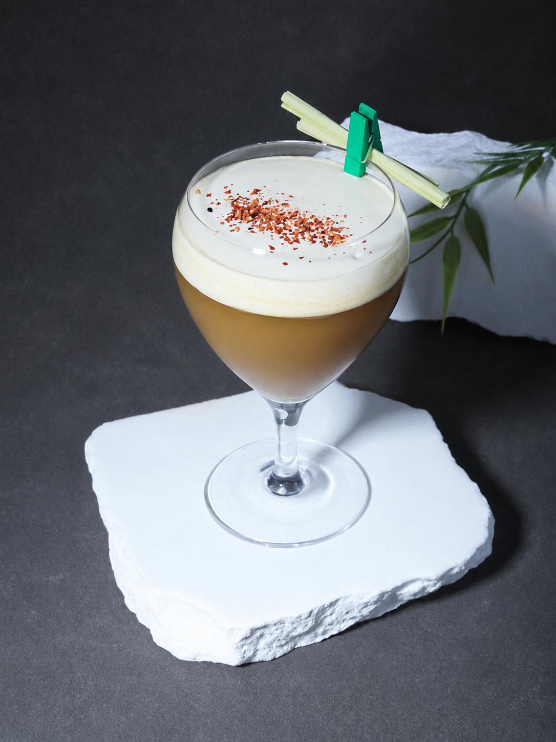 Oat milk coffee topped with roasted tea foam and a lemongrass garnish